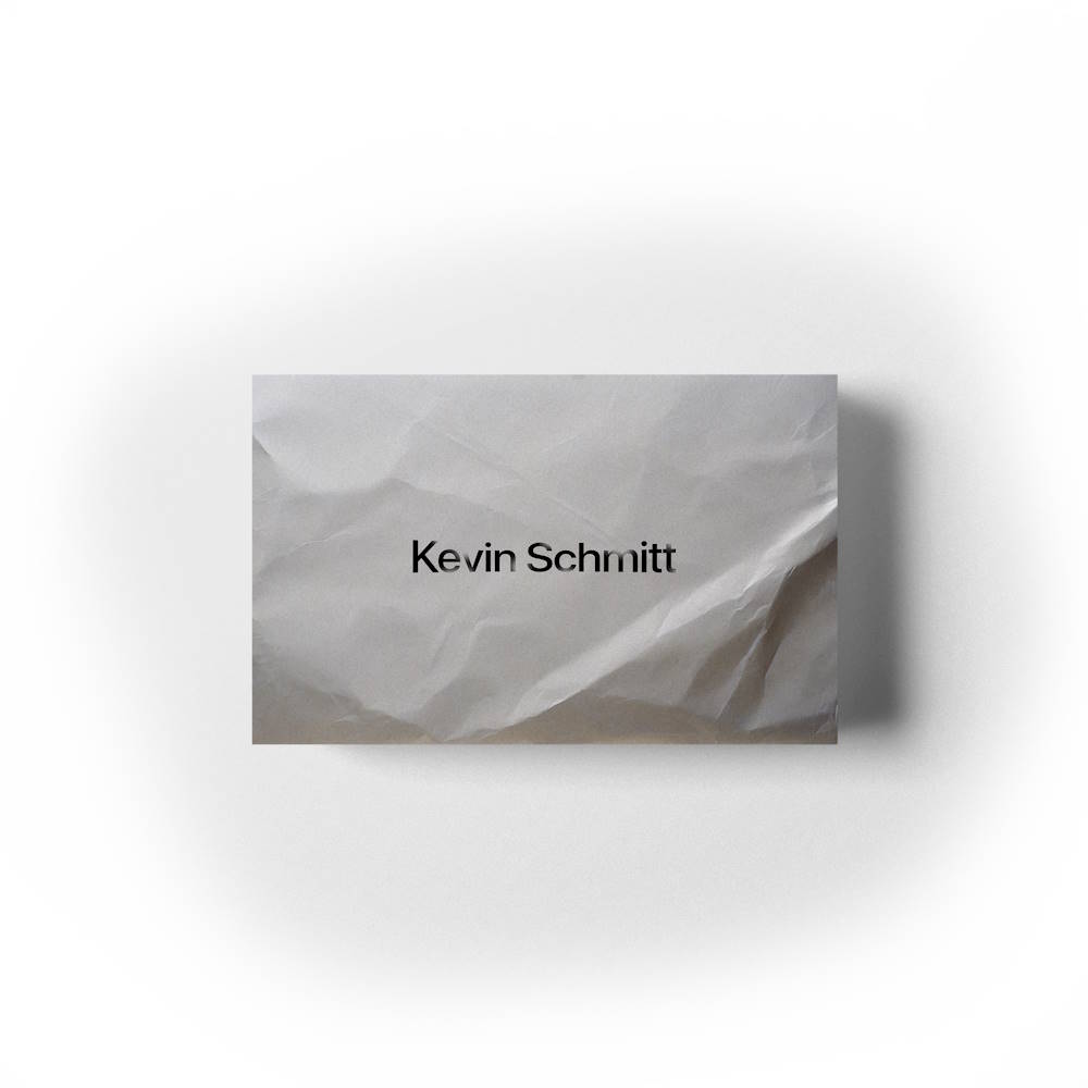 Name "Kevin Schmitt" written on crumpled paper, minimalistic style.